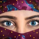 Close-up portrait of a woman with striking eyes and a colorful patterned headscarf.