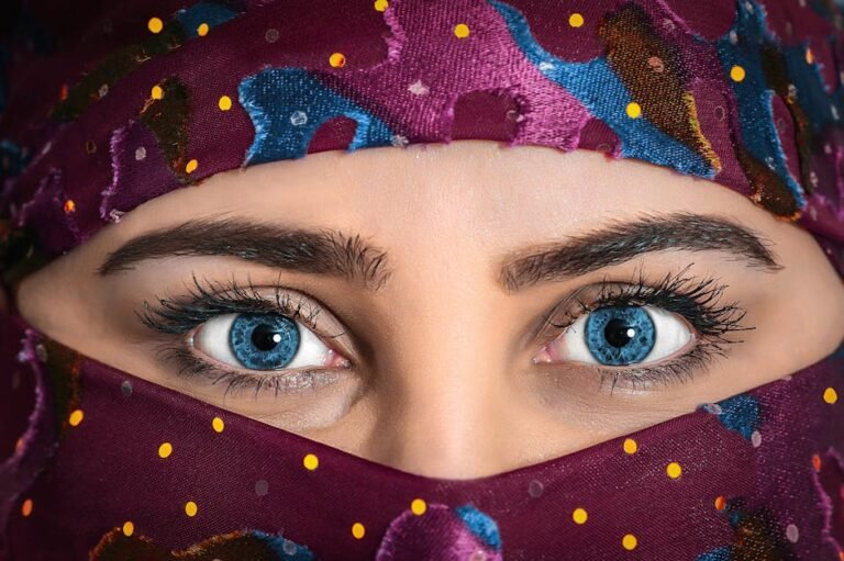 Close-up portrait of a woman with striking eyes and a colorful patterned headscarf.