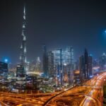 Beautiful night view of Dubai city skyline with Burj Khalifa towering over illuminated roads and skyscrapers.