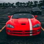 Vibrant red sports car parked in an empty lot with overcast skies.